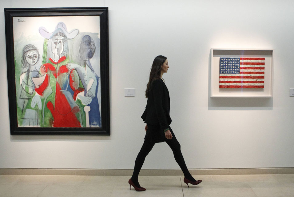 Laura-Vere-Hodge-of-Christies-walks-along-a-gallery-containing-Picassos-Femme-et-Fillettes-L-and-Flag-by-artist-Jasper-Johns